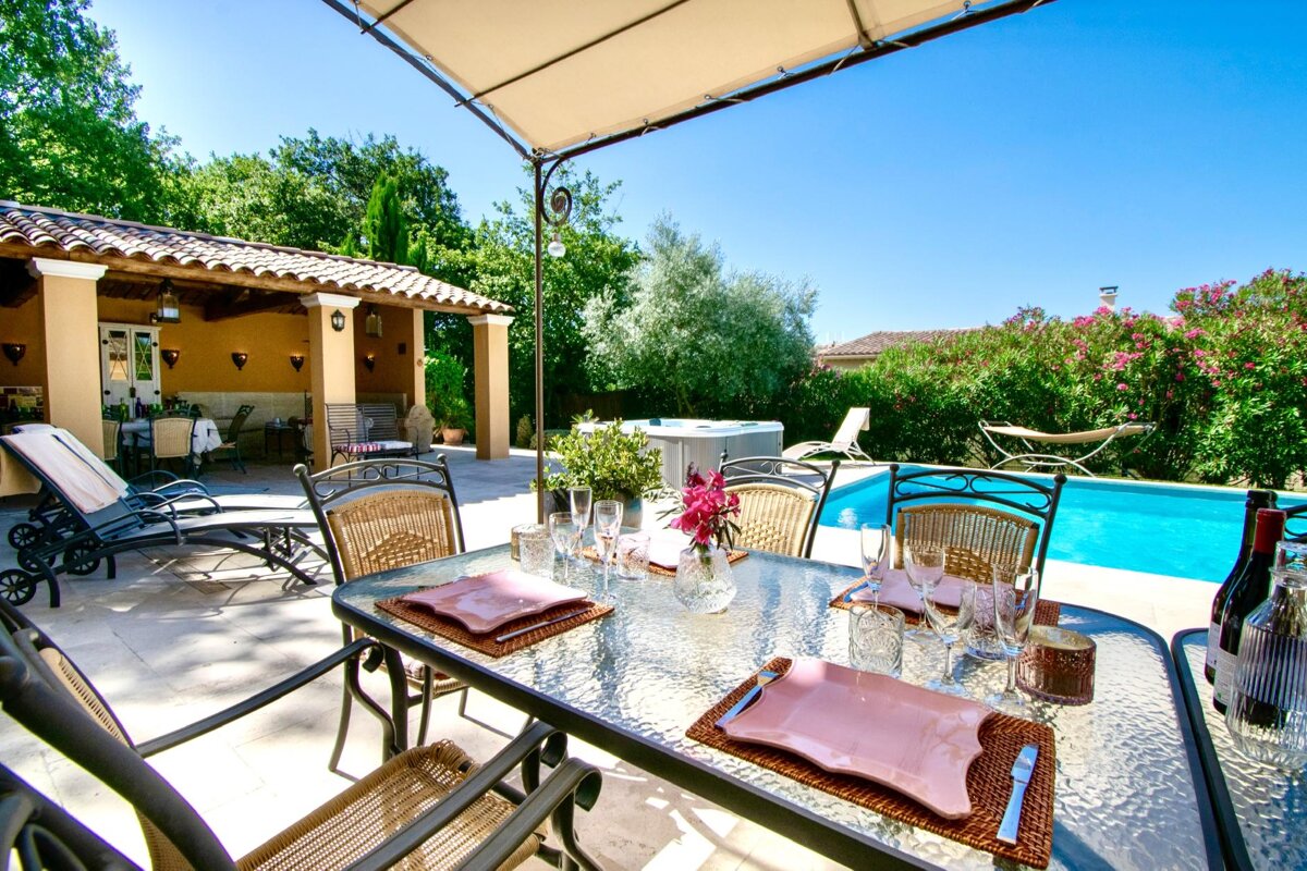 A patio with a table and chairs and a pool in the background