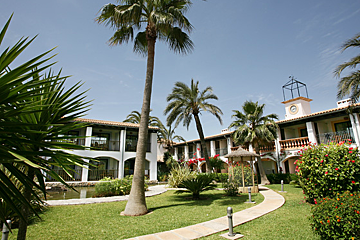 A building with a clock tower and palm trees in front of it