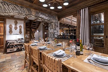 A dining room table with plates and wine bottles on it