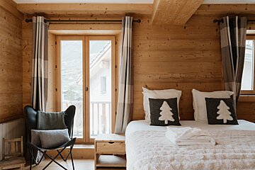 A bedroom with a bed and pillows with trees on them