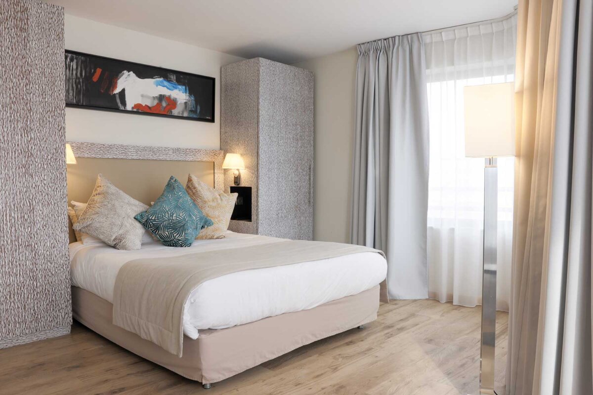 A hotel room with a bed and a painting on the wall