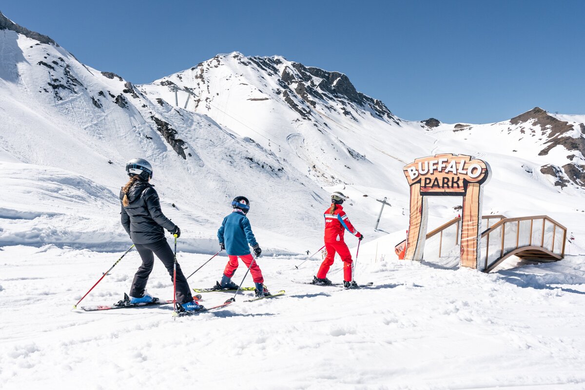 Three skiers, including children, approach the 