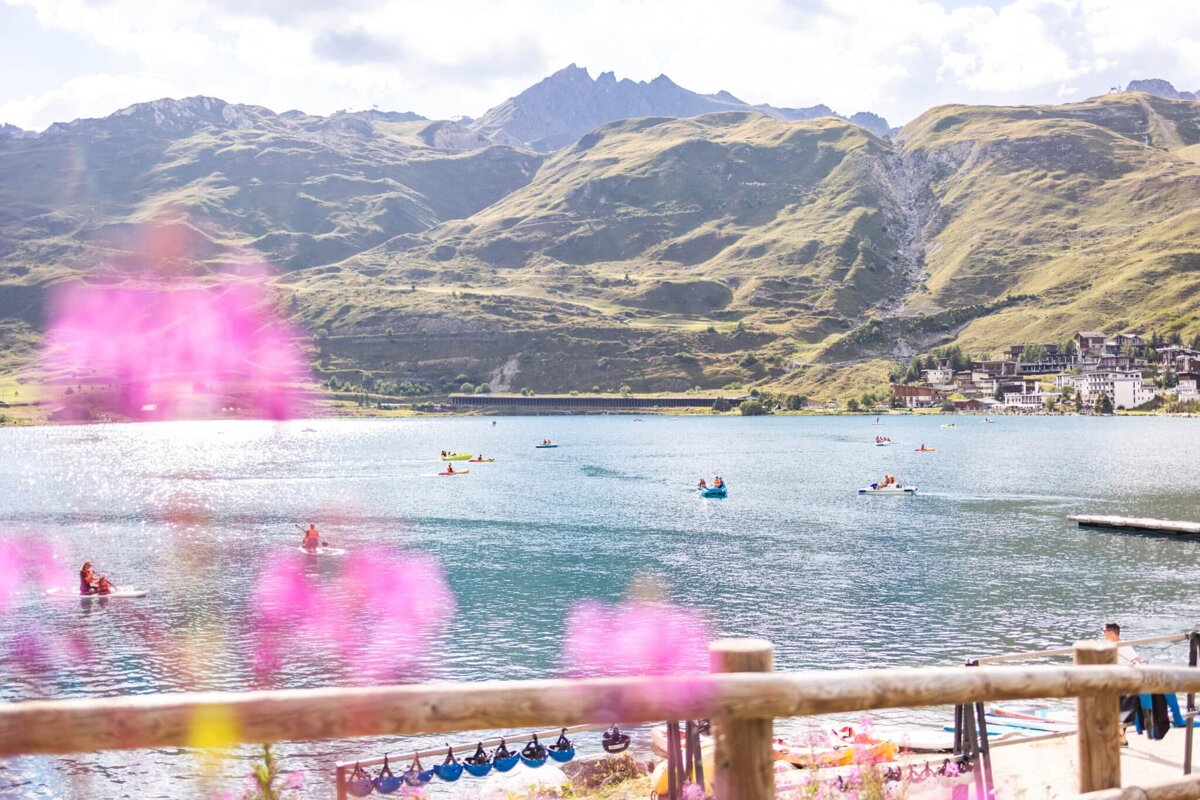 A group of people in kayaks on a lake with mountains in the background