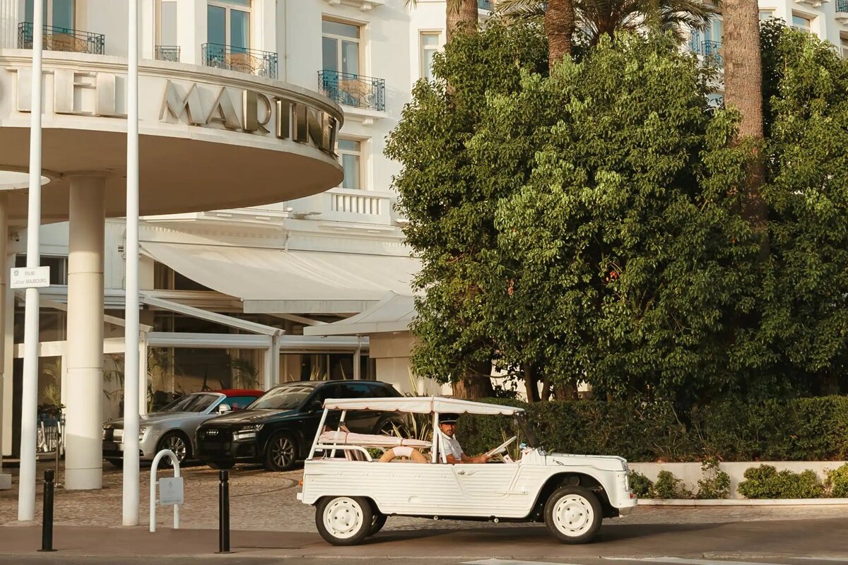 A white car is parked in front of the hotel marine