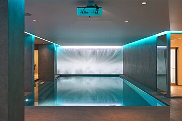 A large indoor swimming pool with a projector hanging from the ceiling