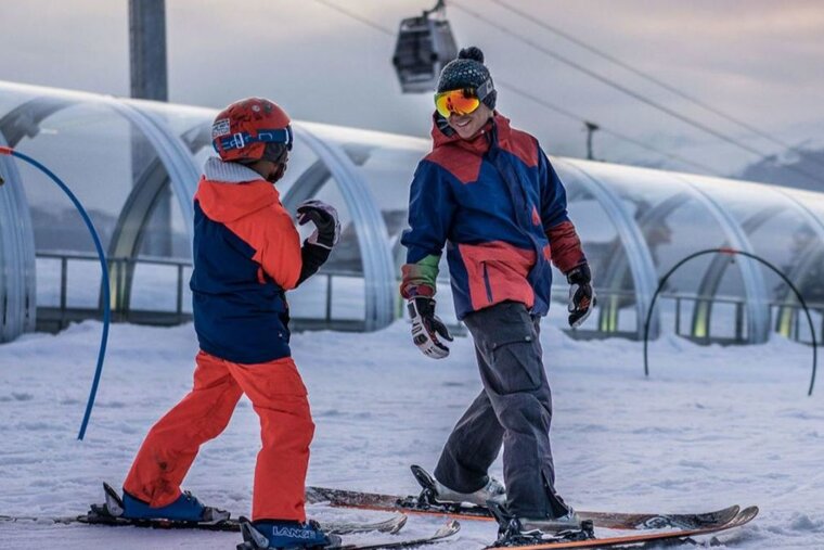 two skiers near a covered magic carpet