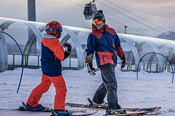two skiers near a covered magic carpet