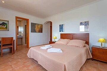 A bedroom with a painting on the wall above the bed