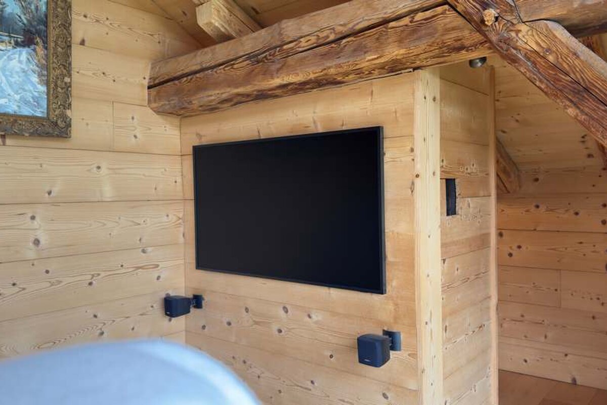A flat screen tv is mounted on a wooden wall