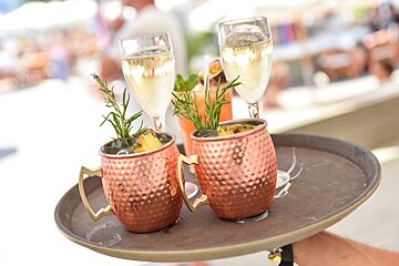 A person holding a tray with two drinks on it