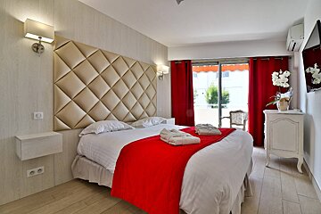 A bed with a red blanket and white sheets in a hotel room