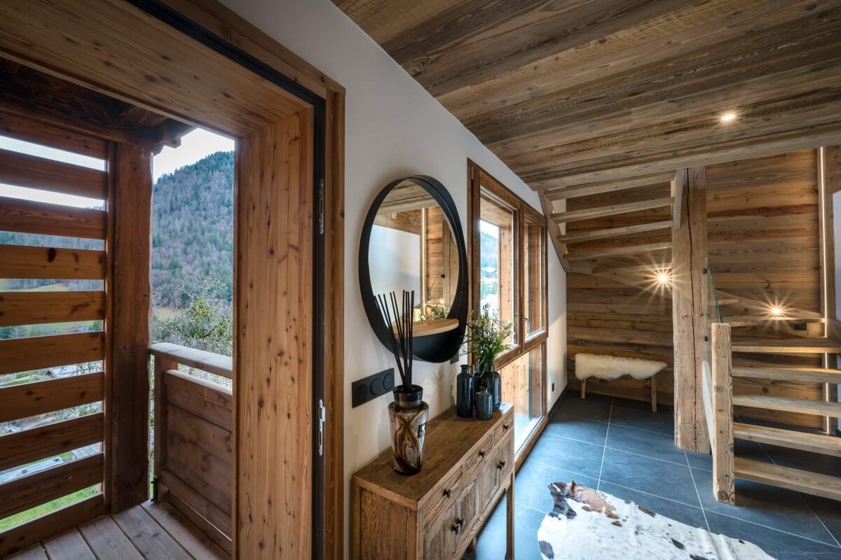 A wooden hallway with a staircase and a mirror