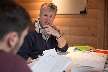 A man sitting at a table with papers and a book that says ' spanish ' on it