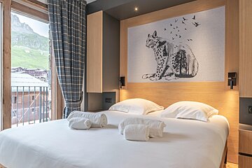 A bed with a picture of a cat on the wall above it