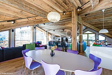 A dining room with purple chairs and a white table