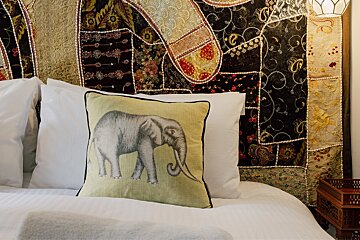 A bed with a pillow with an elephant on it