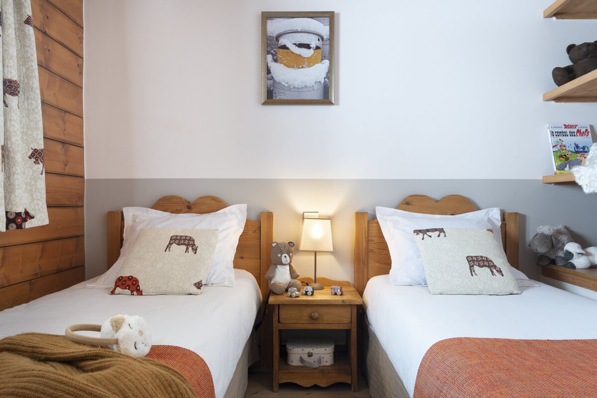 Two twin beds in a bedroom with a picture on the wall above them that says ' la ferme des moutons '