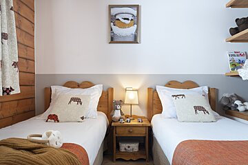 Two twin beds in a bedroom with a picture on the wall above them that says ' la ferme des moutons '