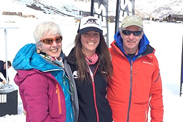 three people smiling at the camera wearing ski jackets