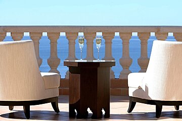 Two chairs and a table with two glasses of champagne on it