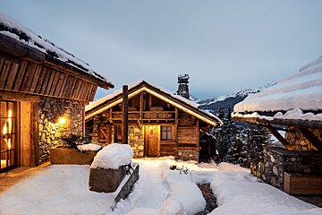 A snowy house with mountains in the background