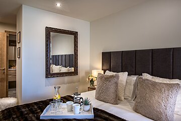 A bedroom with a large mirror and a tray on the bed