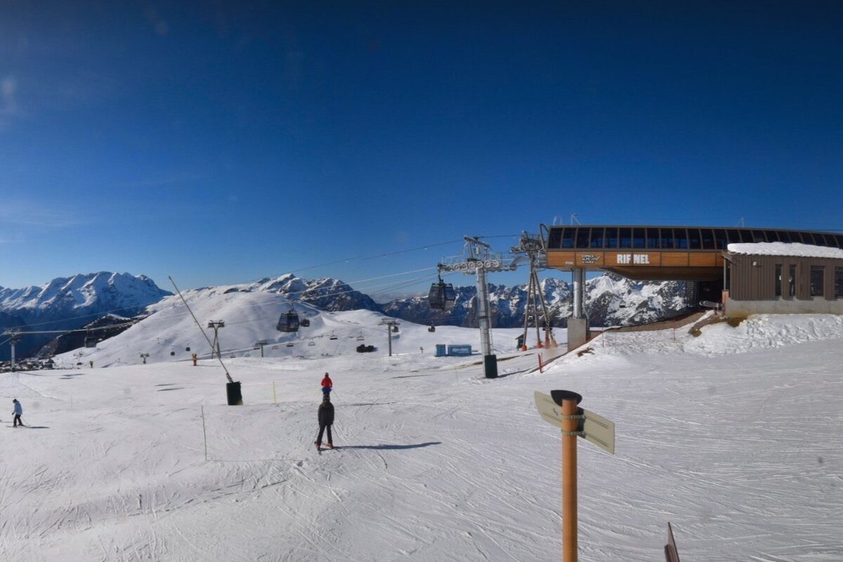 Sunny alpine ski resort with snow-covered mountains, a 