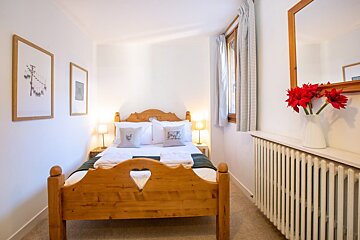 A bedroom with a wooden bed and a mirror