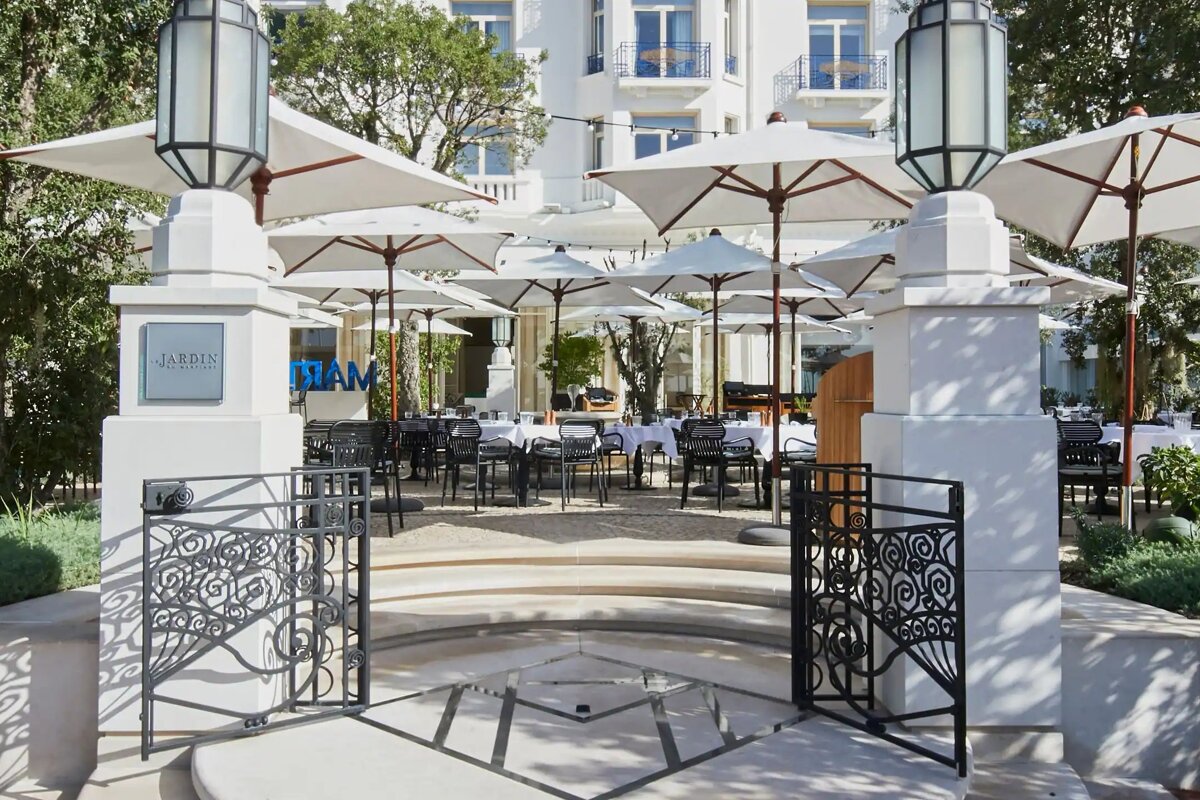 A restaurant with tables and umbrellas and a sign that says jardin
