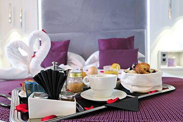 A tray with a cup of coffee on it sits on a bed