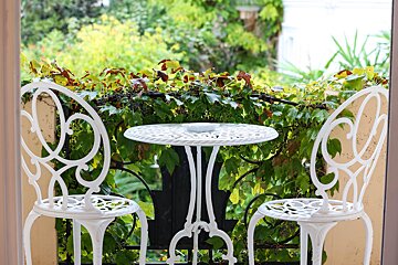 Two white chairs and a white table on a balcony