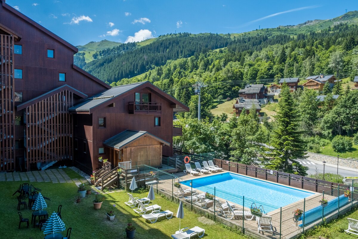 A large swimming pool is surrounded by chairs and umbrellas