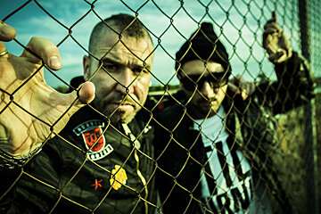Spanish rap group SFDK behind a chain fence