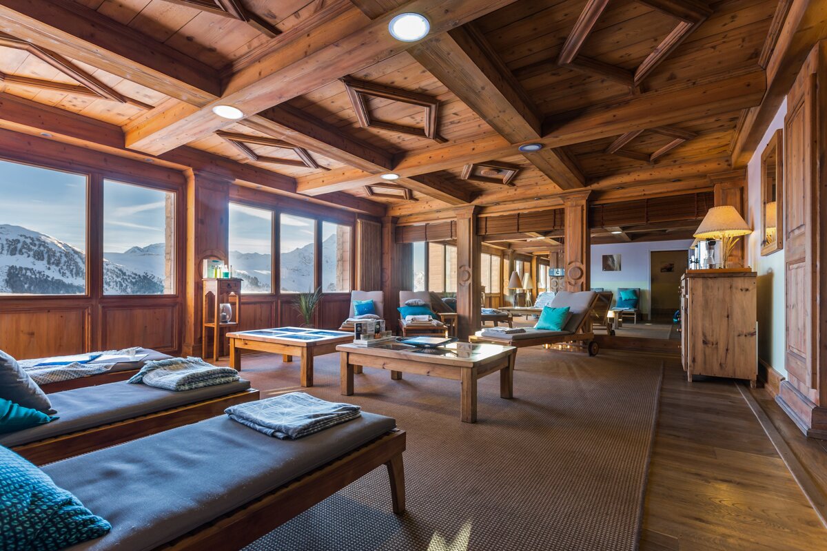 A room with a lot of wooden furniture and a mountain in the background