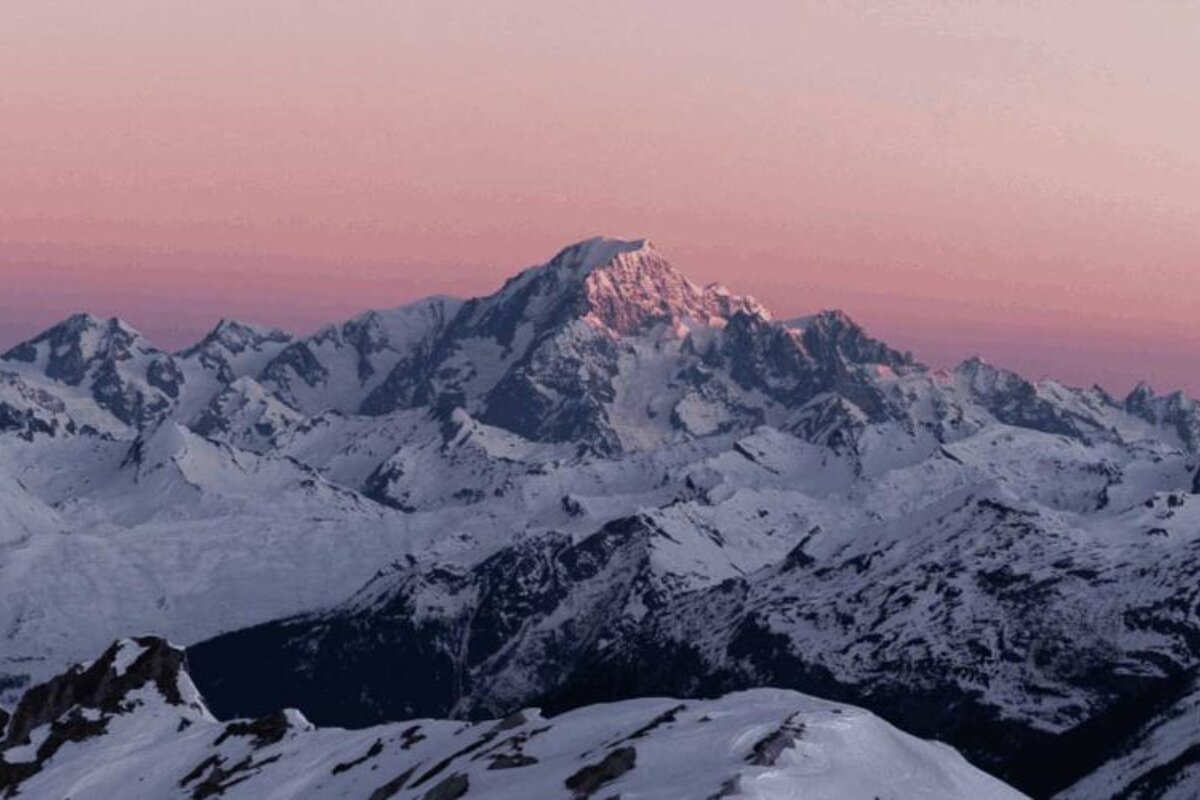 A snowy mountain with a pink sky in the background