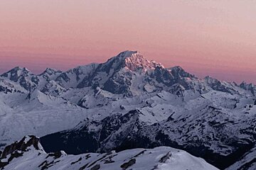 A snowy mountain with a pink sky in the background