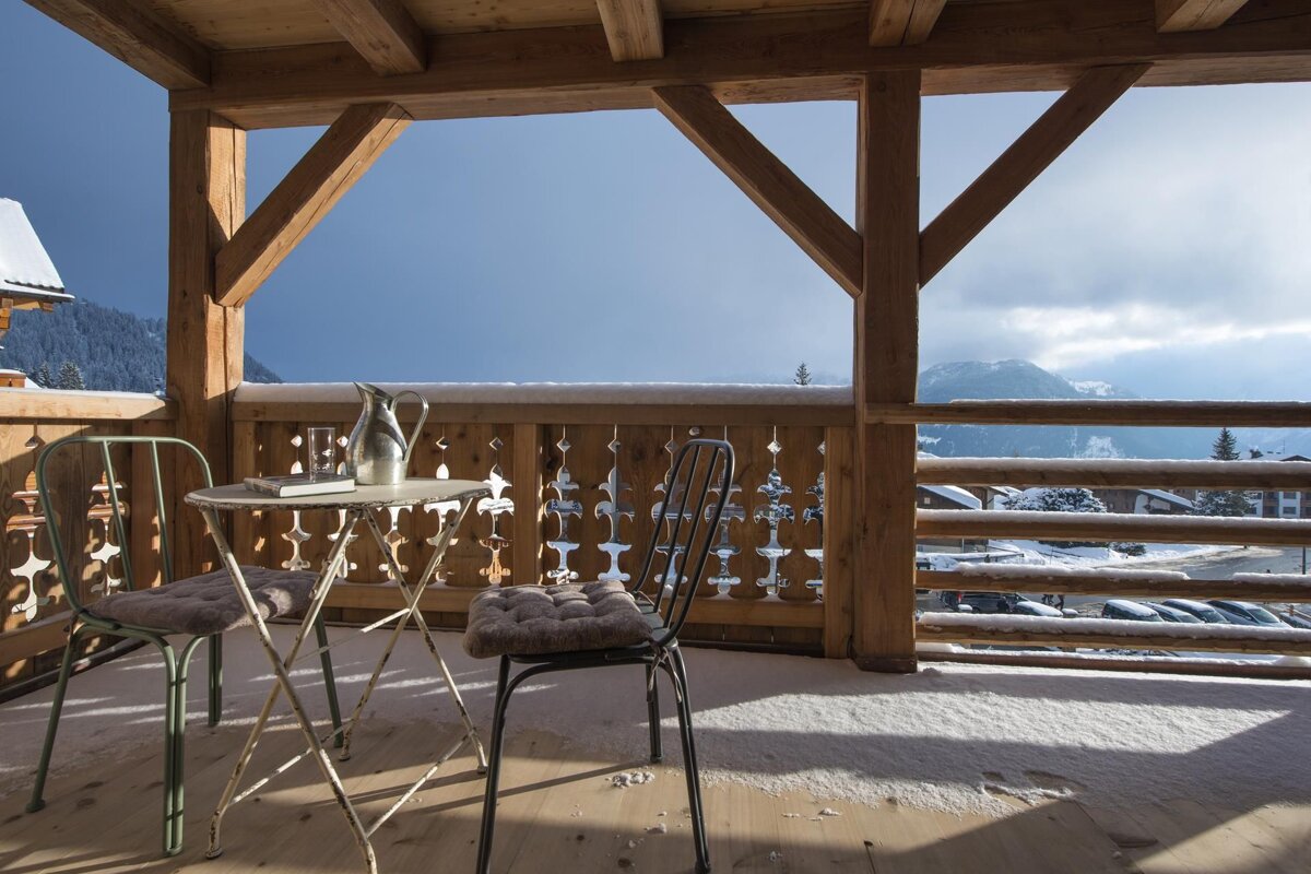 A balcony with a table and chairs and a view of snowy mountains