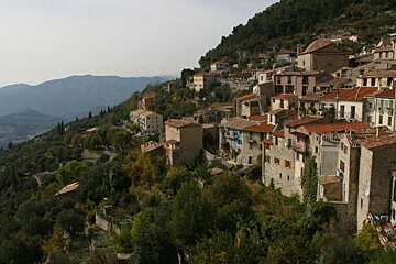 A small village on a hillside with mountains in the background