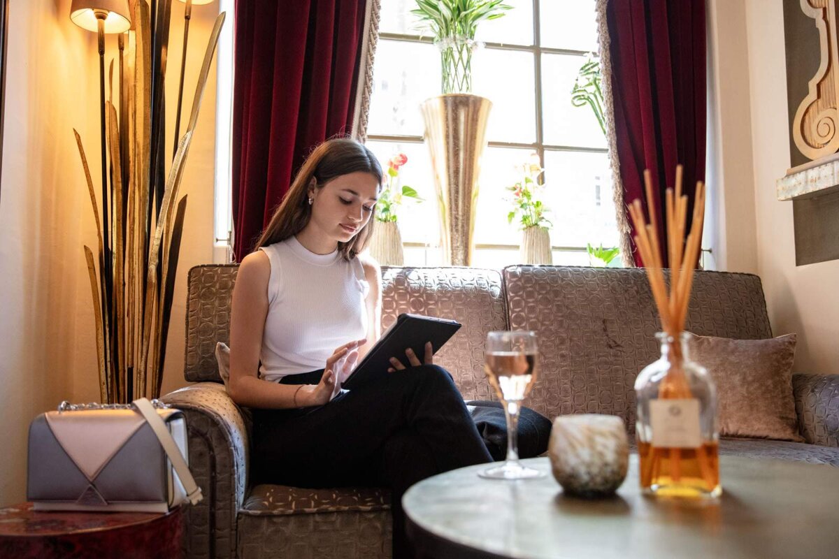 A woman sits on a couch looking at a tablet