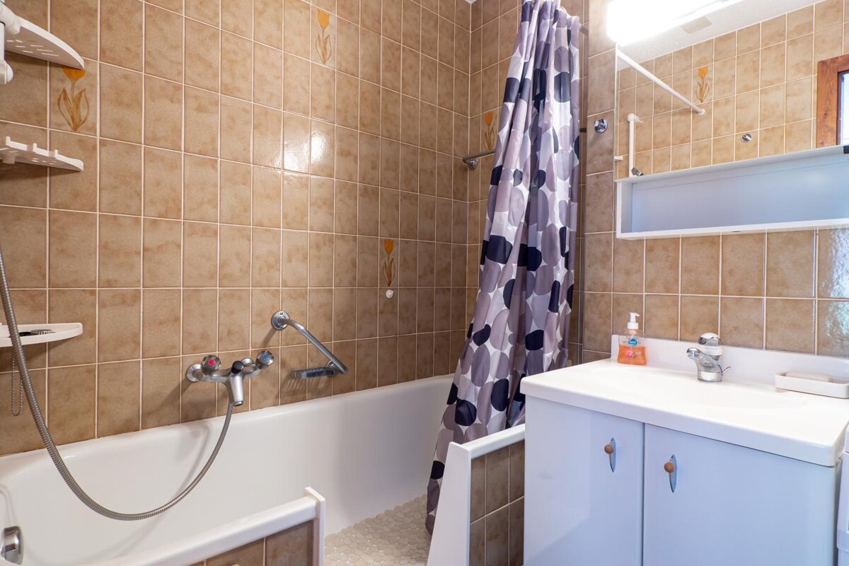 A bathroom with a bathtub a sink and a shower curtain