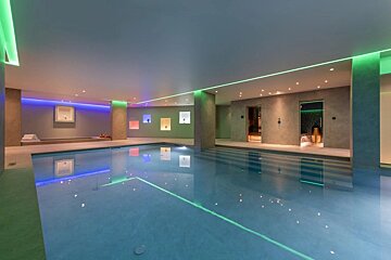 A large indoor swimming pool with green and blue lights