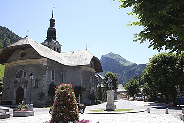 A statue in front of a church with a mountain in the background