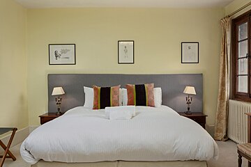 A bedroom with a large bed and two lamps