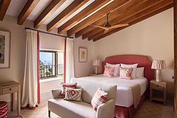 A bedroom with a large bed and a ceiling fan