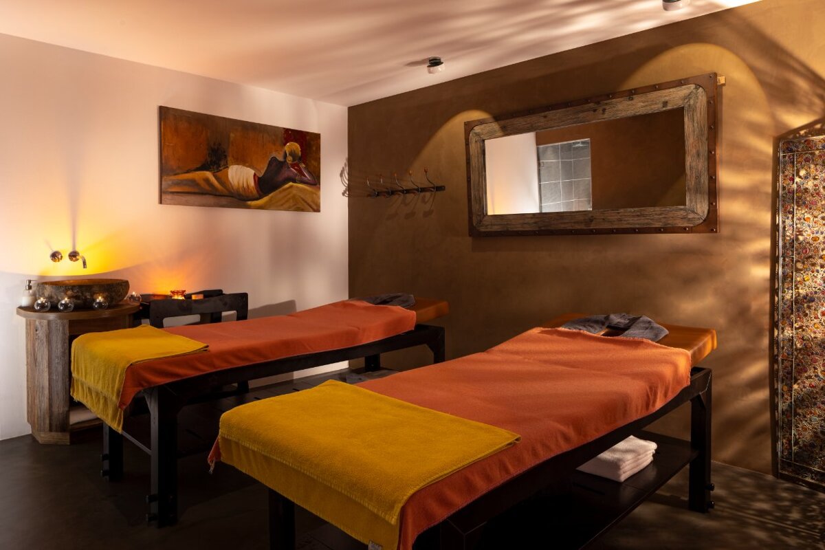 Two massage beds in a room with a painting on the wall above them
