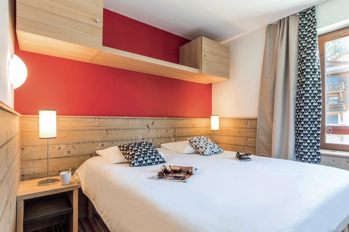 A bed with a magazine on it in a hotel room