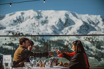 A group of people toasting with wine glasses in front of a snowy mountain