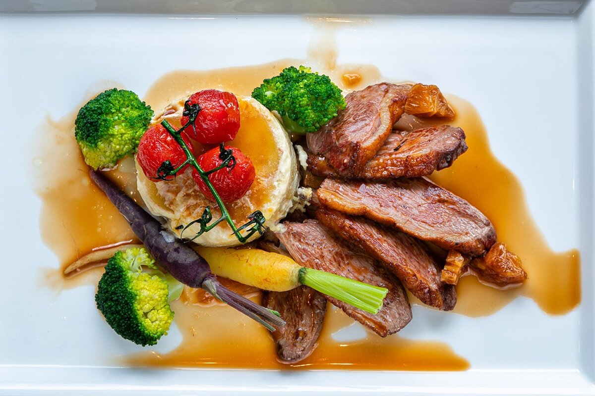 A white plate topped with meat broccoli and tomatoes