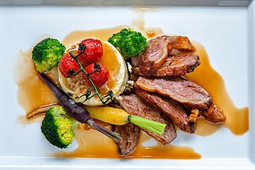 A white plate topped with meat broccoli and tomatoes