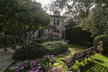 A garden with a bench and a statue in front of a house